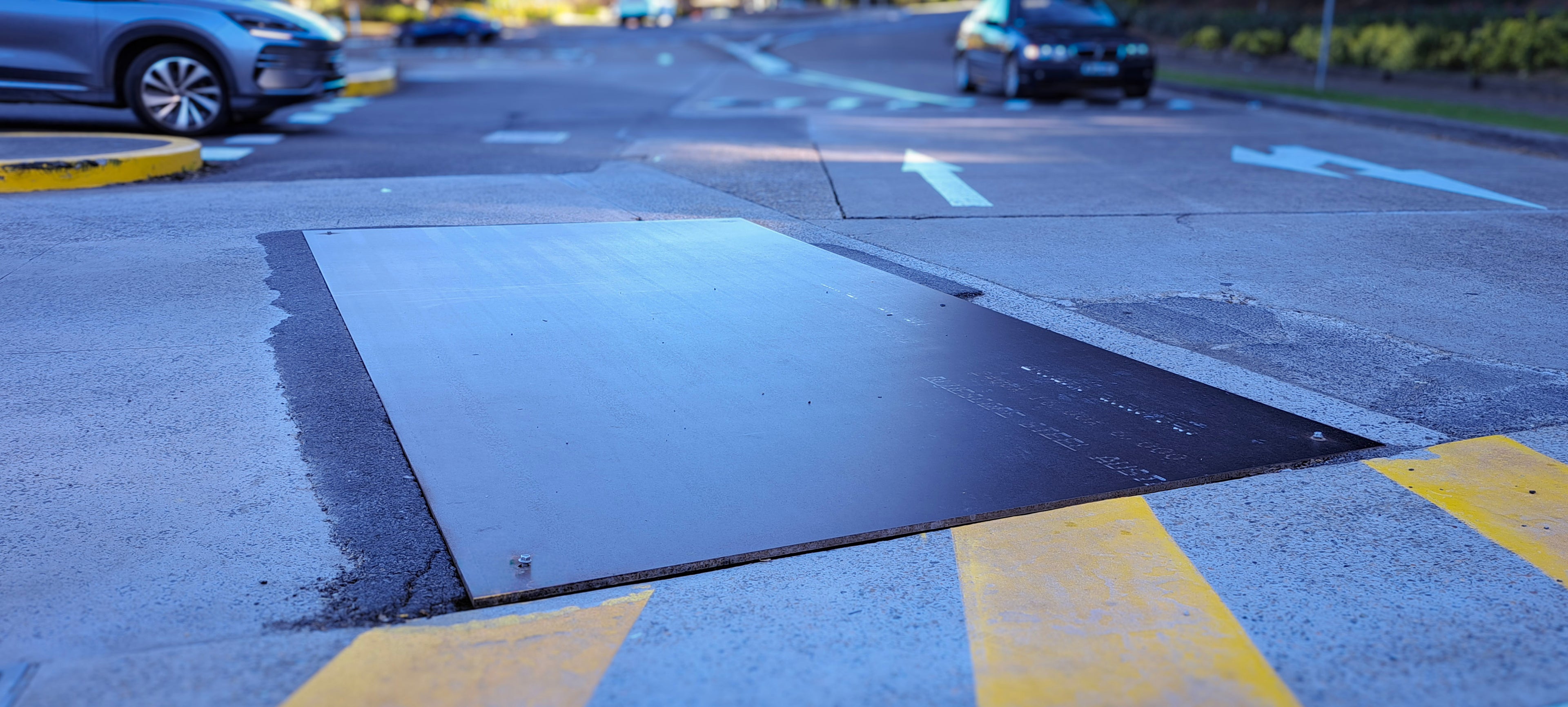 Road with steel plate cover in the middle, cars on the sides